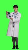 Front view Woman doctor examines x ray scan to find disease diagnosis for patient, looking at radiography results to determine illness and cure. Medic standing against greenscreen backdrop. Camera A. video