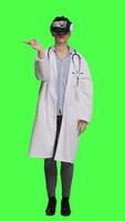 Front view Physician consulting patients with virtual reality futuristic glasses, wears white coat against greenscreen backdrop. General practitioner uses artificial intelligence interactive headset. Camera A. video