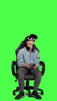 Front view Woman playing video games using virtual reality headset in studio, enjoying cyberspace 3d gaming tournament against greenscreen backdrop. Gamer having fun with vr glasses. Camera A.