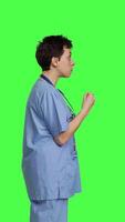 Profile Stressed furious nurse screaming at someone against greenscreen backdrop, showing rage and anger in studio. Aggressive upset medical assistant shouting and being dissatisfied. Camera B. video