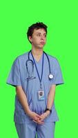 Front view Stressed nurse checking time on watch and waiting for patient to arrive at checkup examination, being impatient against greenscreen backdrop. Medical assistant with scrubs and stethoscope. Camera B. video