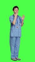 Side view Medical assistant feeling extremely sleepy against greenscreen backdrop, being overworked after the night shift. Woman nurse yawns and feels exhausted in studio, burnout and anxiety. Camera A. video