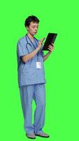 Side view Nurse doing online shopping with credit card banking transaction, paying for items on store website. Medical assistant purchasing things on internet, e commerce ordering against greenscreen. Camera A. video