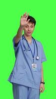 Front view Woman nurse waving hello and inviting people to come closer, calling over patients for checkup examinations against greenscreen. Medical assistant greeting persons and asking them to come. Camera B. video