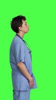 Profile Displeased nurse saying no and sighing against greenscreen backdrop, acting disappointed while she wears blue scrubs. Medical assistant with expertise shows negative gesture, being tired. Camera B. video