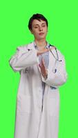 Front view Woman physician doing timeout gesture against greenscreen backdrop, asking for a work break after multiple examinations. Doctor showing pause or stop symbol, feeling tired. Camera B. video