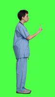 profil missnöjd irriterad sjuksköterska skrikande Nej och argumenterar med någon mot grönskärm bakgrund, som visar rasa och ilska medan hon bär sjukhus skrubbar. aggressiv medicinsk assistent. kamera a. video