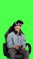 Front view Player using virtual reality glasses to have fun on cyberspace gaming competition, playing video games and winning. Gamer against greenscreen backdrop uses vr headset and controller. Camera B.