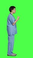 Profile Stressed furious nurse screaming at someone against greenscreen backdrop, showing rage and anger in studio. Aggressive upset medical assistant shouting and being dissatisfied. Camera A. video