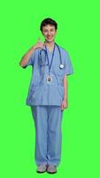 Front view Cheerful nurse giving thumbs up sign against greenscreen backdrop, showing positive gesture with a like. Medical assistant shows her approval, recommending something and being satisfied. Camera A. video