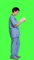 Profile Medical assistant reading a literature book against greenscreen backdrop, enjoying healthcare industry lecture to acquire new expertise. Nurse paying attention to medicine manual at work. Camera A. video