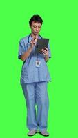 Front view Nurse doing online shopping with credit card banking transaction, paying for items on store website. Medical assistant purchasing things on internet, e commerce ordering against greenscreen. Camera A. video