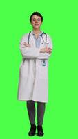 Front view Portrait of successful physician standing with arms crossed against greenscreen backdrop, wearing a white coat and stethoscope. Doctor feeling confident with healthcare expertise. Camera A. video