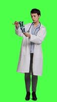 Front view Woman doctor examines x ray scan to find disease diagnosis for patient, looking at radiography results to determine illness and cure. Medic standing against greenscreen backdrop. Camera A. video