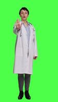 Front view Woman physician raising palm and doing stop sign in studio, expressing rejection and denial against greenscreen backdrop. General practitioner showing warning symbol with negative reaction. Camera A. video
