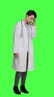 sida se olycklig läkare som handlar om med en smärtsam migrän mot grönskärm bakgrund, arbetssätt i sjukvård industri under tryck. kvinna läkare lidande från en huvudvärk, överarbetad. kamera a. video