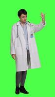 Side view Friendly physician inviting people to come closer to her against greenscreen backdrop, calling patients over and smiling. General practitioner asking persons to approach her. Camera A. video