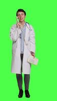 Front view Physician answering landline phone call against greenscreen backdrop, talking to patients about checkup appointments. Medic having remote discussion on retro telephone with cord. Camera A. video