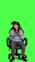 Front view Happy gamer winning video games tournament with vr glasses, playing mobile gaming championship using her smartphone and virtual reality interactive headset. Greenscreen backdrop. Camera A.