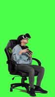 Side view Happy gamer winning video games tournament with vr glasses, playing mobile gaming championship using her smartphone and virtual reality interactive headset. Greenscreen backdrop. Camera A.