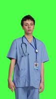 Front view Health specialist with blue scrubs showing stop sign in studio, standing against greenscreen backdrop. Nurse expressing denial and refusal with warning forbidden symbol, denying something. Camera B. video