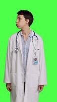 Vorderseite Aussicht Frau Arzt suchen um zum Patienten zu Kommen Sie beim Untersuchung Prüfungen, warten zum jemand Stehen gegen grüner Bildschirm Hintergrund. Allgemeines Praktiker mit Weiß Mantel Gefühl ungeduldig. Kamera b. video