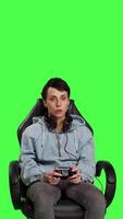 Front view Excited proud player winning at video games online tournament, sitting in a gaming chair against greenscreen backdrop. Woman gamer feeling happy after her e sport competition success. Camera B.