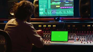 audio technicus werken met muziek- opname software en bewerken deuntjes, menging troosten en controle paneel bord in post productie studio. producent in werking technisch apparatuur. camera a. video