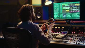 sonido diseñador trabajando en pista grabación con audio profesional software, operando técnico equipo en panel tablero en controlar habitación. audio ingeniero mejora música alto calidad. cámara una. video