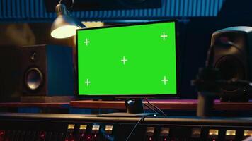 Sound designer editing and recording tracks with mixing console in control room, twisting knobs and pressing key buttons. Audio engineer producing music with greenscreen on monitor. Camera A. video