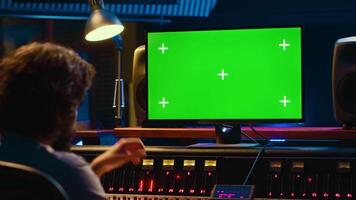 Audio expert editing tracks by following online lesson on greenscreen pc, mixing new tunes together to create a song. Sound engineer working in control room to record and process music. Camera A. video