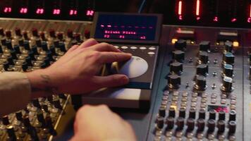 Sound designer working with sliders and switchers on control desk in professional music recording studio, editing and producing songs for a new album. Technician adjusting volume levels. Camera A. video