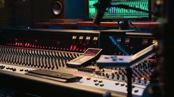 Control room with technical equipment and music recording software, professional studio editing and producing tracks. Audio console with moving faders and colored meters, high quality sounds. video