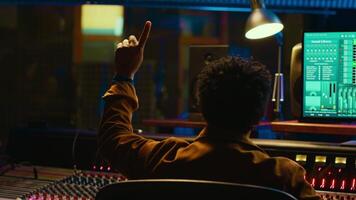 African american audio engineer counting down singer in sound booth, preparing to record and process tracks in control room. Producer twisting knobs and faders to enhance tune quality. Camera A. video