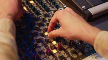 Audio technician twisting pre amp knobs and buttons on panel board in control room, using editing console for mixing and mastering tracks. Professional tracking engineer in music studio. Camera A. video