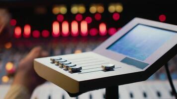 Audio engineer working with mixing console and motorized faders in control room to create music at professional recording studio. Technician producer editing recordings in soundproof space. Camera A. video