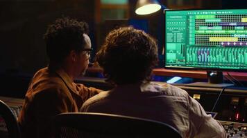 musik produktion team granskning volym nivåer på audio programvara, använder sig av blandning och behärska tekniker till skapa en träffa låt. musiker och ljud designer arbete på redigering spelade in spår. kamera a. video