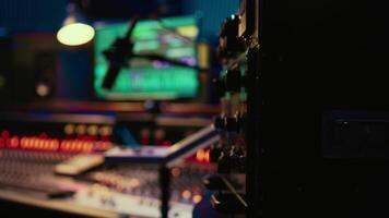 Control room desk equipped with motorized faders and amplifier used in mixing and mastering tracks with audio console. Empty soundproof studio with sliders and switchers on board. video