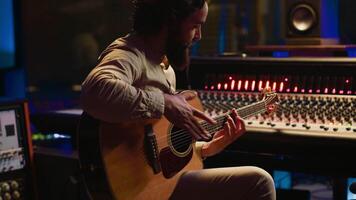 Jeune artiste auteur compositeur composition une Nouveau chanson sur guitare dans enregistrement session à studio, création airs et édition leur après dans Publier production. musicien compositeur produisant des pistes. caméra un. video