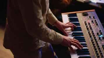 Musiker spielen Klavier Midi- Regler im Steuerung Zimmer beim Fachmann Aufzeichnung Studio, Erstellen Geräusche mit elektronisch Tastatur Anmerkungen. Klang Ingenieur tut mischen und Meister auf Dateien. Kamera a. video