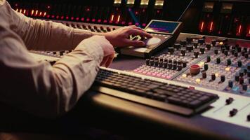 Sound designer working with sliders and switchers on control desk in professional music recording studio, editing and producing songs for a new album. Technician adjusting volume levels. Camera B. video