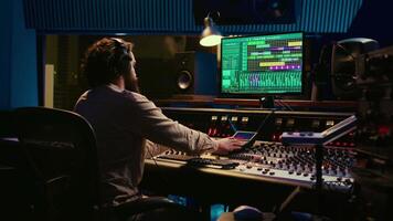 Using audio editing software, sound producer creates tunes and handling technical equipment on a control room dashboard. Technician music producer increases tracks quality. Camera B. video