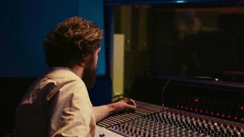 Music producer fixing coiled cable inside amplifier or audio compressor, prepares control room technical equipment for a recording session. Sound engineer works on producing tracks. Camera B. video