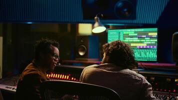 nöjd konstnär och spårning ingenjör håller på med hög fem gest efter skapande en låt tillsammans, Lycklig med de slutlig resultat. team av sångare och producent fira framgångsrik Spår samarbeta. kamera b. video