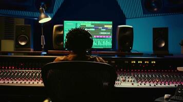 Music producer recording and editing tracks in control room, pressing buttons to create sound effects in post production. Audio technician operates on professional studio equipment. Camera B. video