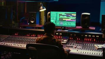 africain américain du son producteur édition des pistes sur l'audio Logiciel et console, ajustement le volume les niveaux et ajouter effets dans Publier production. technicien produisant Nouveau frappé chanson dans studio. caméra b. video