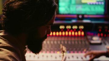 Young artist songwriter composing a new song on guitar in recording session at studio, creating tunes and editing them after in post production. Musician composer producing tracks. Camera B. video