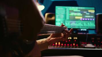 Skilled artist guitarist recording a new song with electro acoustic guitar, composing and editing music in professional studio control room. Young musician songwriter creating tunes. Camera A. video