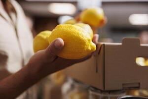 hombre adquisitivo limones crecido por cero residuos supermercado propietario en su jardín, cerca arriba. cliente contento a encontrar eco simpático pesticidas gratis Fresco frutas en local almacenar, borroso antecedentes foto