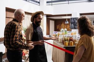 Newly opened zero waste shop owner inviting customers in after preparing organic environmentally conscious bulk products stock. Entrepreneur cutting ribbon, celebrating new local store inauguration photo